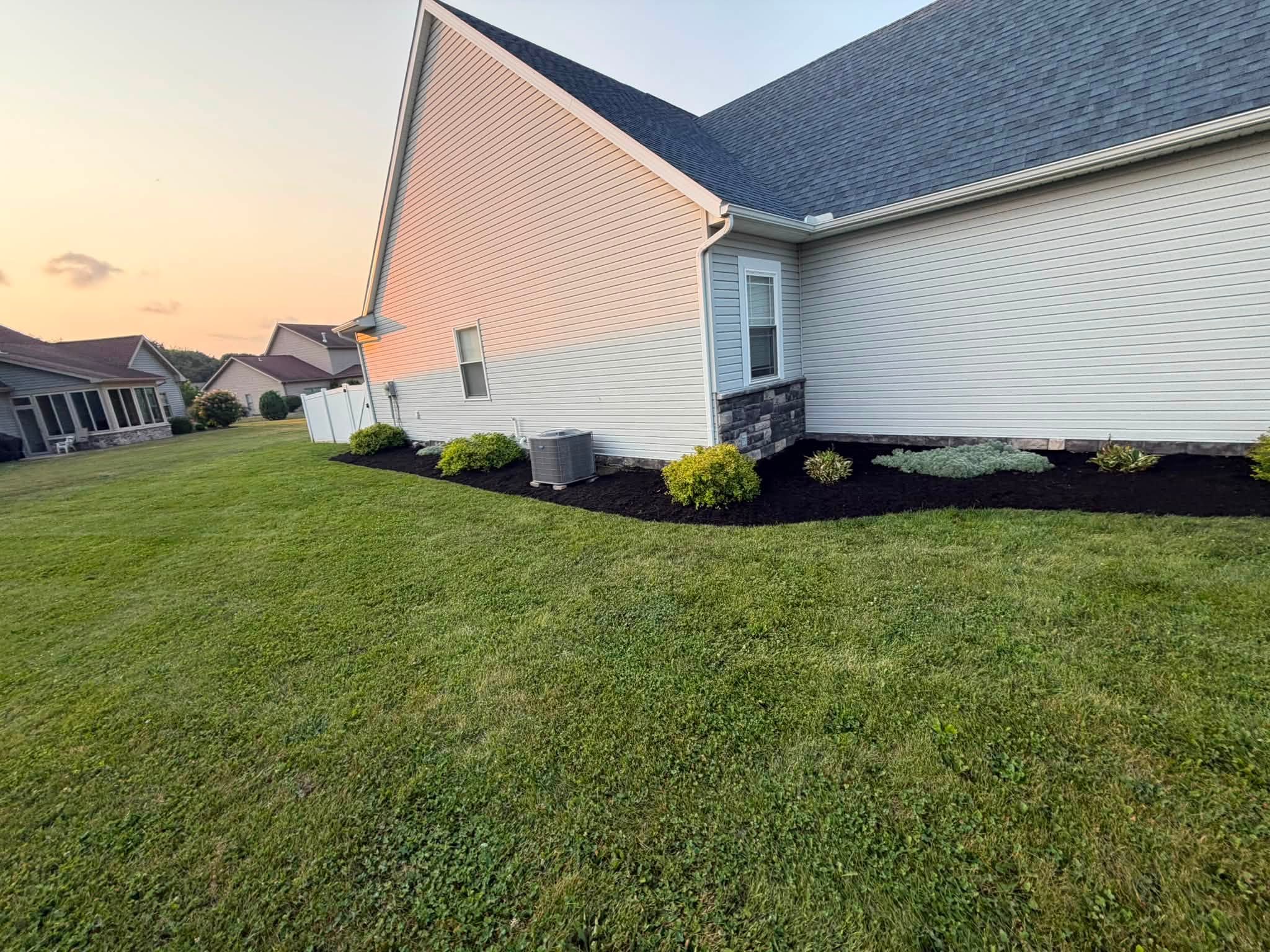 Fresh black mulch and tidy shrubs along the side of a home
